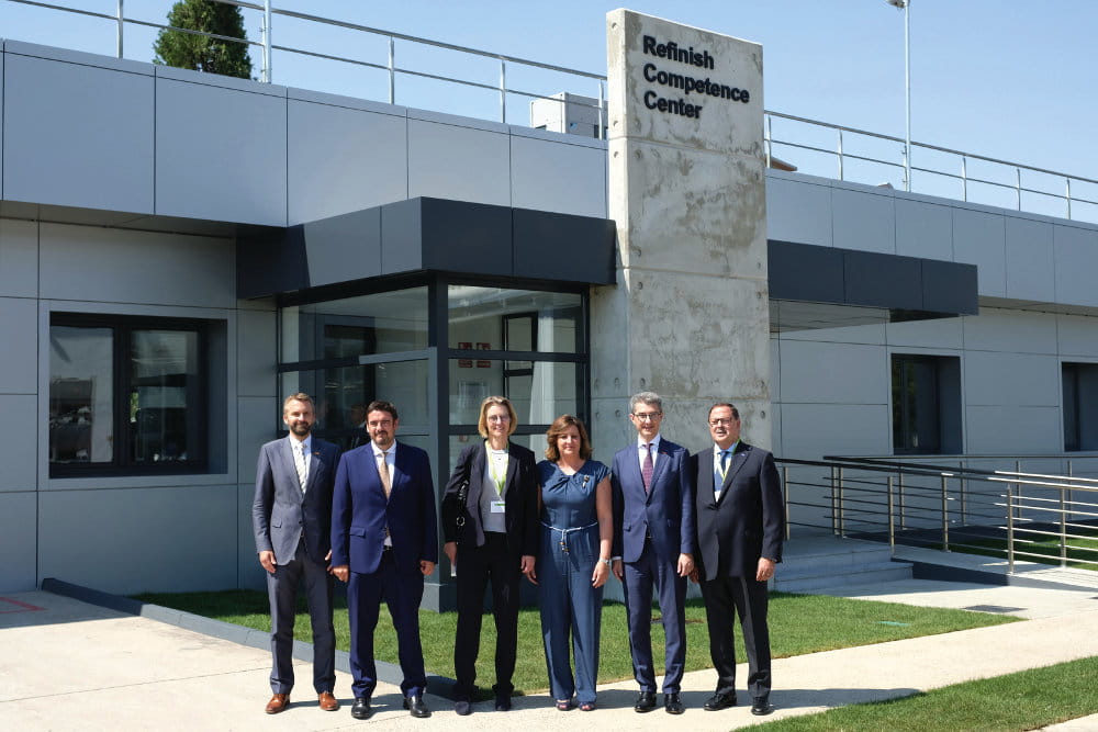 Four men and two women in front of a building with the inscription "Refinish Center".